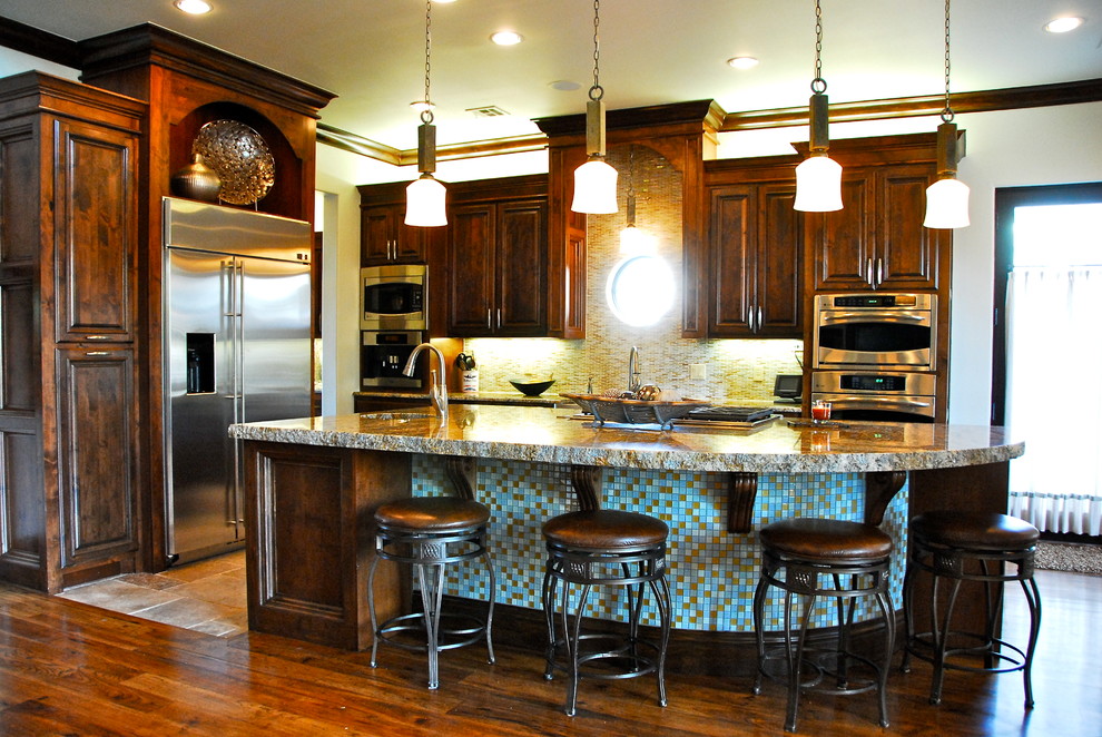 Eat-in kitchen - transitional l-shaped eat-in kitchen idea with an undermount sink, blue cabinets, granite countertops, glass tile backsplash, stainless steel appliances and raised-panel cabinets