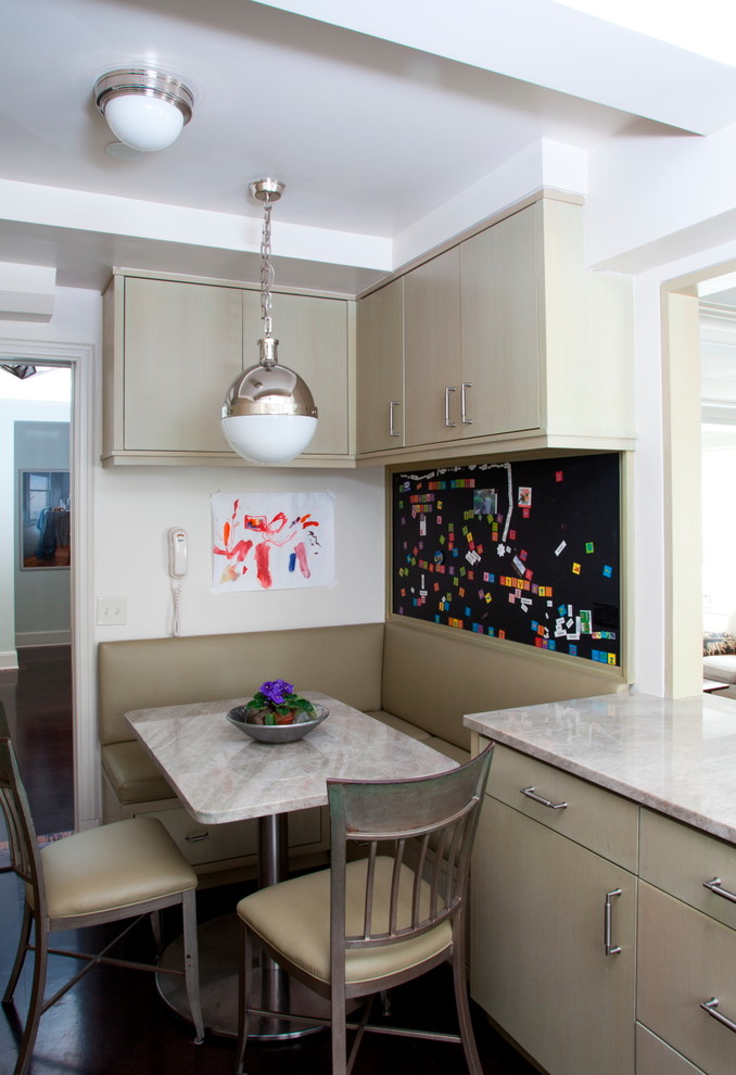 Mid-sized transitional eat-in kitchen in New York with flat-panel cabinets and beige cabinets.