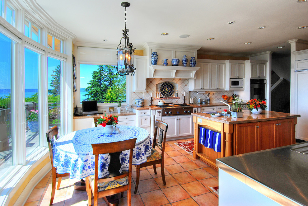 Elegant u-shaped terra-cotta tile eat-in kitchen photo in Seattle with recessed-panel cabinets, white cabinets, beige backsplash, paneled appliances, an undermount sink, granite countertops and ceramic backsplash