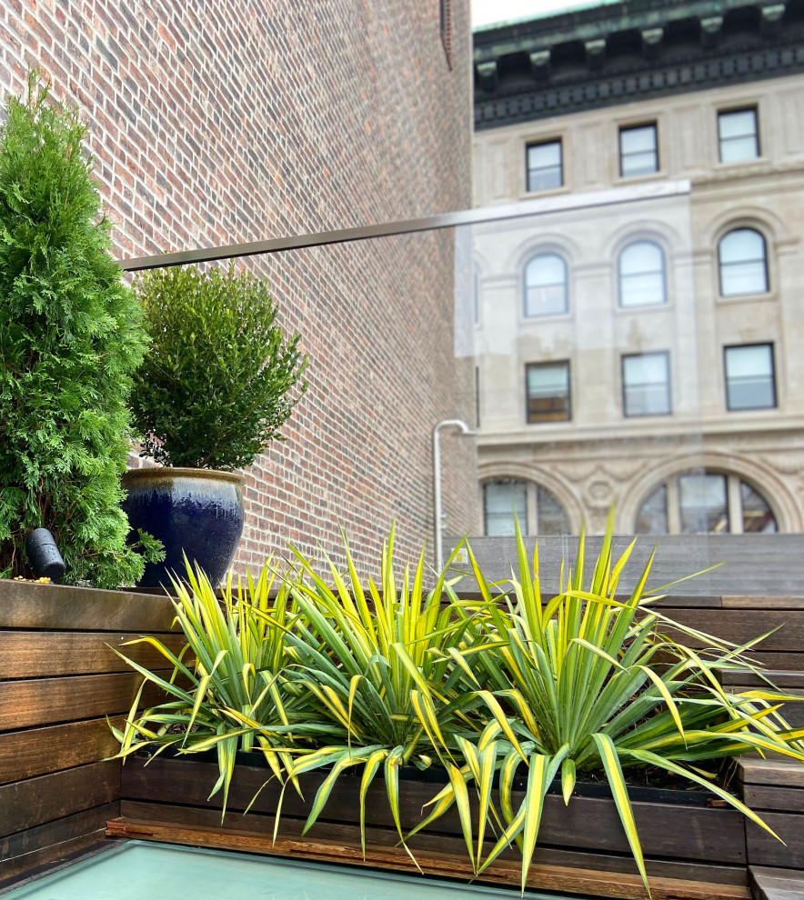 Design ideas for a contemporary rooftop partial sun garden for fall in New York with a container garden and natural stone pavers.