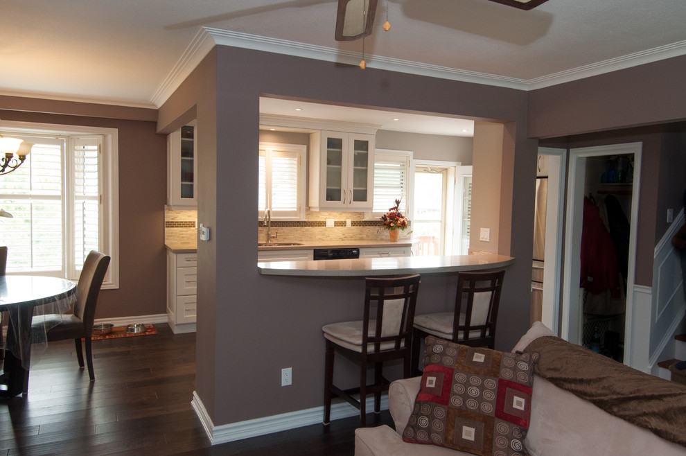 Mid-sized transitional u-shaped dark wood floor eat-in kitchen photo in Toronto with a double-bowl sink, shaker cabinets, white cabinets, beige backsplash, stone tile backsplash, no island, granite countertops and black appliances