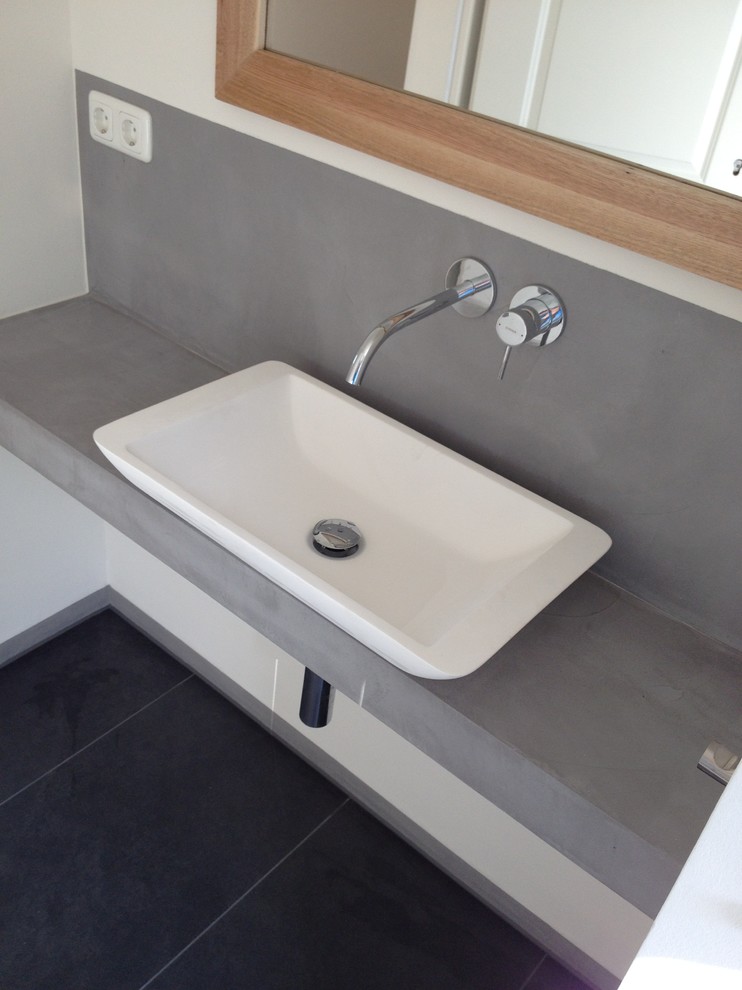 Duschbad With grauen Schränken, Wandtoilette, weißer Wandfarbe, Aufsatzwaschbecken, Beton-Waschbecken/Waschtisch, grauem Boden and Falttür-Duschabtrennung in Cologne