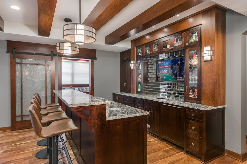 This is an example of a large traditional home bar in Minneapolis with medium hardwood floors and brown floor.