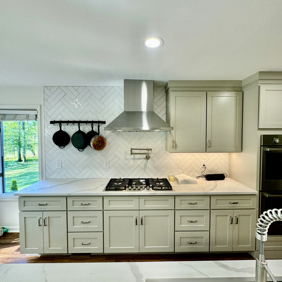 Example of a mid-sized transitional u-shaped medium tone wood floor and brown floor open concept kitchen design in Atlanta with an undermount sink, shaker cabinets, granite countertops, white backsplash, stainless steel appliances, an island, white countertops and beige cabinets
