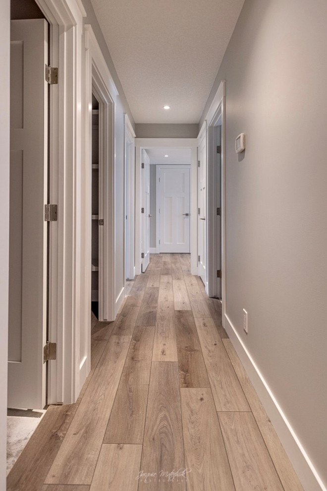 Photo of a large transitional hallway in Calgary with beige walls, vinyl floors and brown floor.