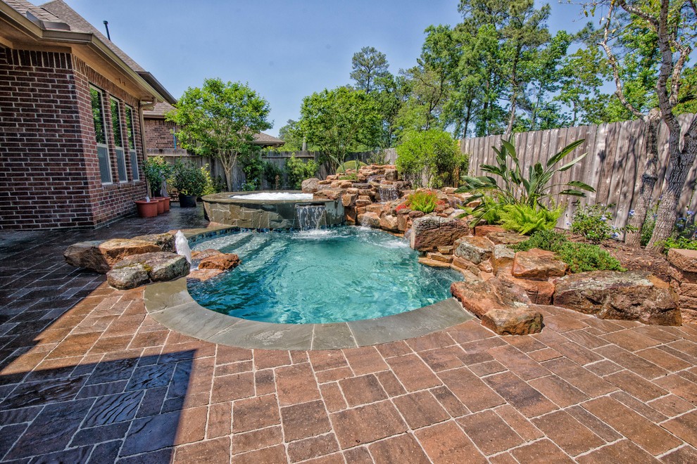 Transitional backyard custom-shaped natural pool in Houston with a hot tub.