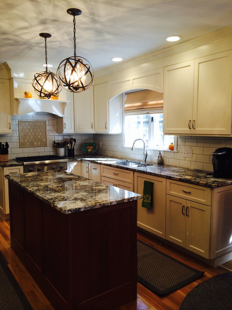 Inspiration for a large transitional l-shaped medium tone wood floor and brown floor kitchen remodel in Boston with an undermount sink, shaker cabinets, white cabinets, granite countertops, white backsplash, subway tile backsplash, stainless steel appliances and an island