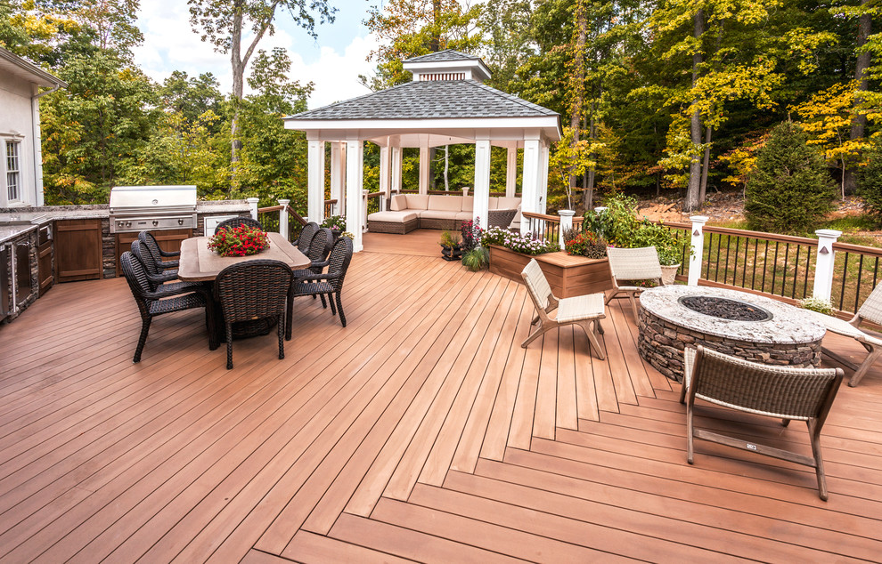 This is an example of a large transitional backyard deck in New York with no cover and a fire feature.