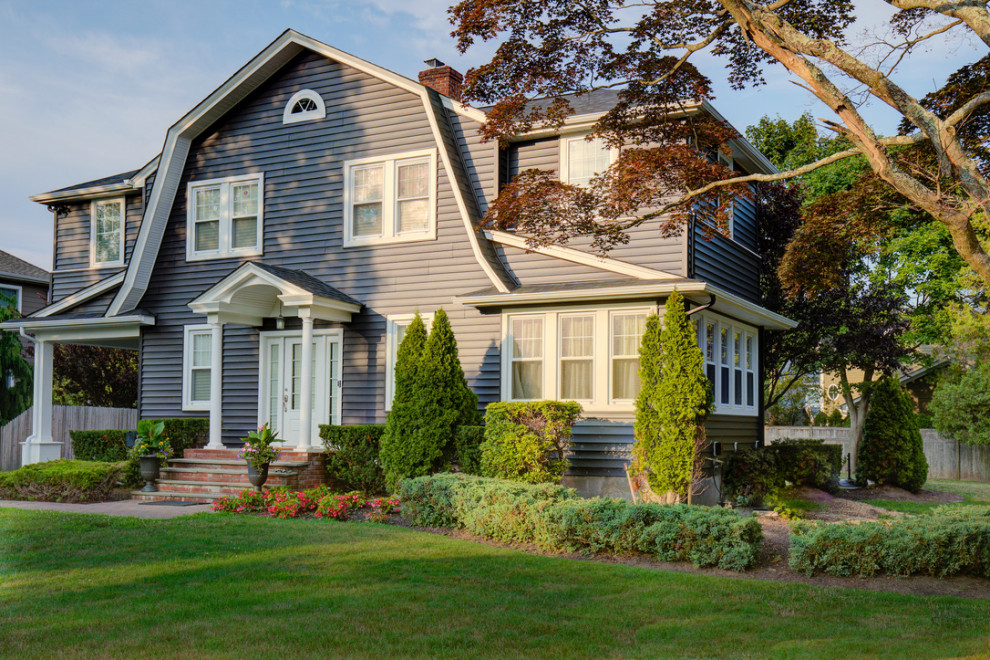 This is an example of a large traditional two-storey black house exterior in Other with vinyl siding, a gambrel roof, a shingle roof, a black roof and clapboard siding.