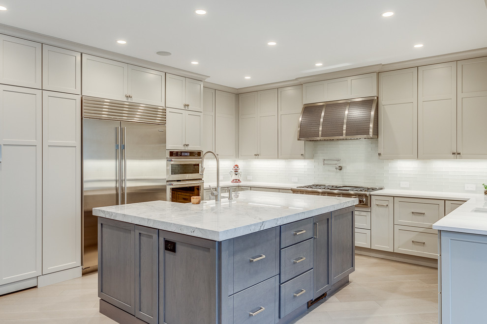 Design ideas for a large transitional u-shaped eat-in kitchen in DC Metro with a farmhouse sink, shaker cabinets, grey cabinets, quartzite benchtops, white splashback, glass tile splashback, stainless steel appliances, medium hardwood floors, multiple islands, grey floor and grey benchtop.