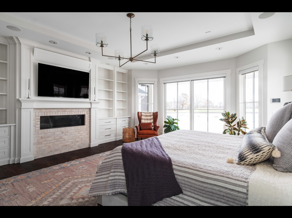 Design ideas for a large country master bedroom in Other with white walls, dark hardwood floors, a ribbon fireplace and a brick fireplace surround.