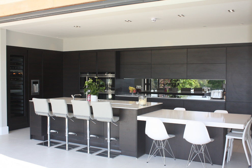 Photo of a mid-sized modern l-shaped open plan kitchen in Other with flat-panel cabinets, quartzite benchtops, metallic splashback, mirror splashback, stainless steel appliances and multiple islands.