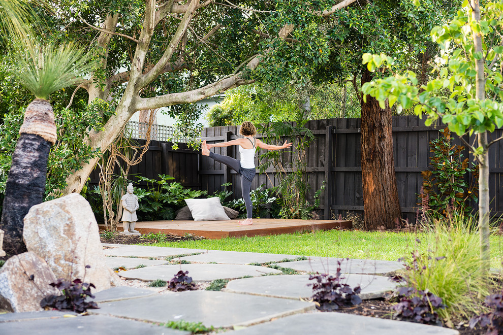 Large modern backyard shaded garden in Melbourne with natural stone pavers.