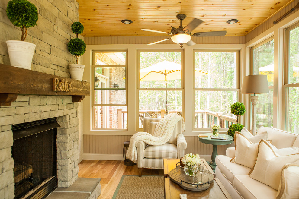 Photo of a sunroom in Charlotte with light hardwood floors, a two-sided fireplace, a stone fireplace surround and a standard ceiling.