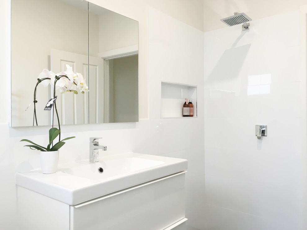 Design ideas for a mid-sized contemporary kids bathroom in Melbourne with flat-panel cabinets, white cabinets, a drop-in tub, a curbless shower, white tile, ceramic tile, white walls, ceramic floors, an undermount sink and engineered quartz benchtops.