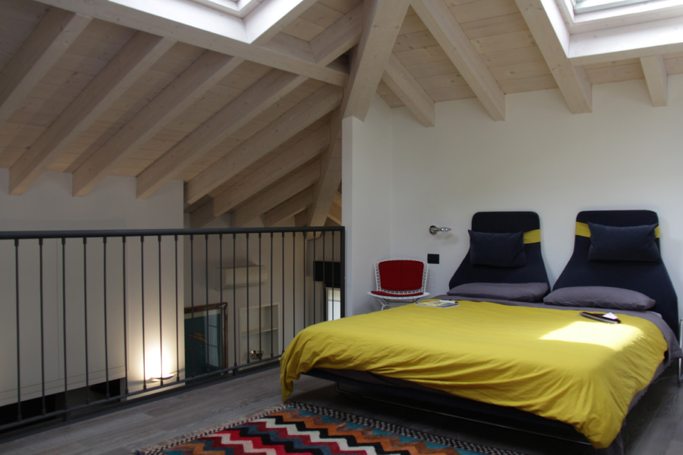 Design ideas for an expansive contemporary loft-style bedroom in Milan with white walls and medium hardwood floors.