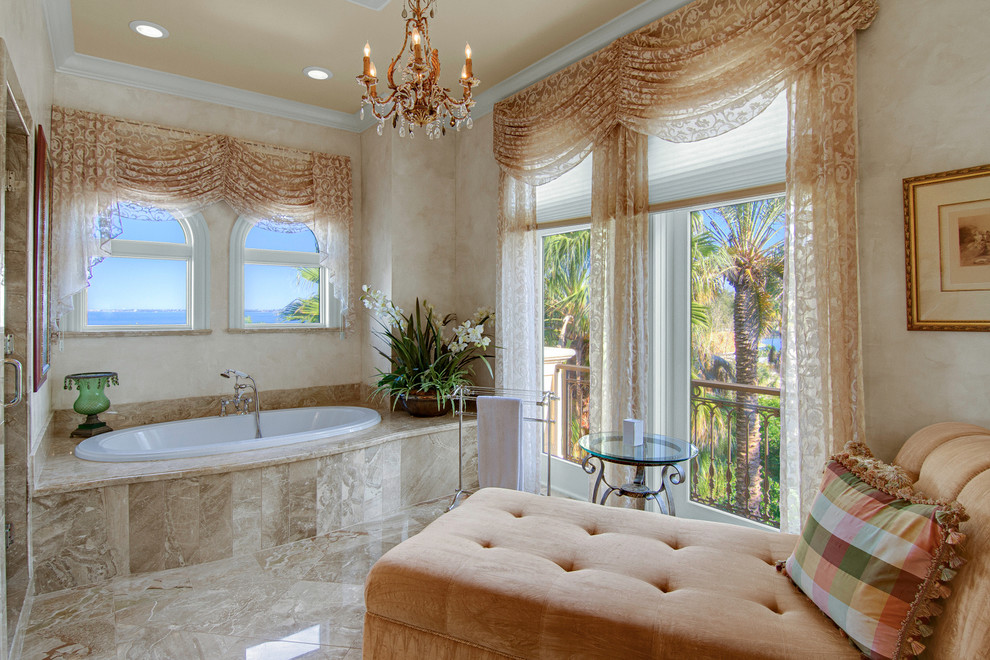 Design ideas for a mediterranean bathroom in Tampa with a drop-in tub and beige tile.