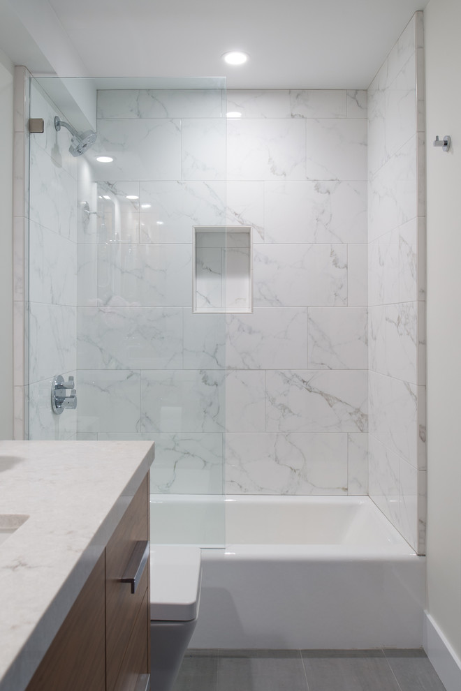 This is an example of a small contemporary bathroom in San Diego with flat-panel cabinets, dark wood cabinets, an alcove shower, a one-piece toilet, white tile, marble, white walls, ceramic floors, an undermount sink, engineered quartz benchtops, grey floor and a hinged shower door.