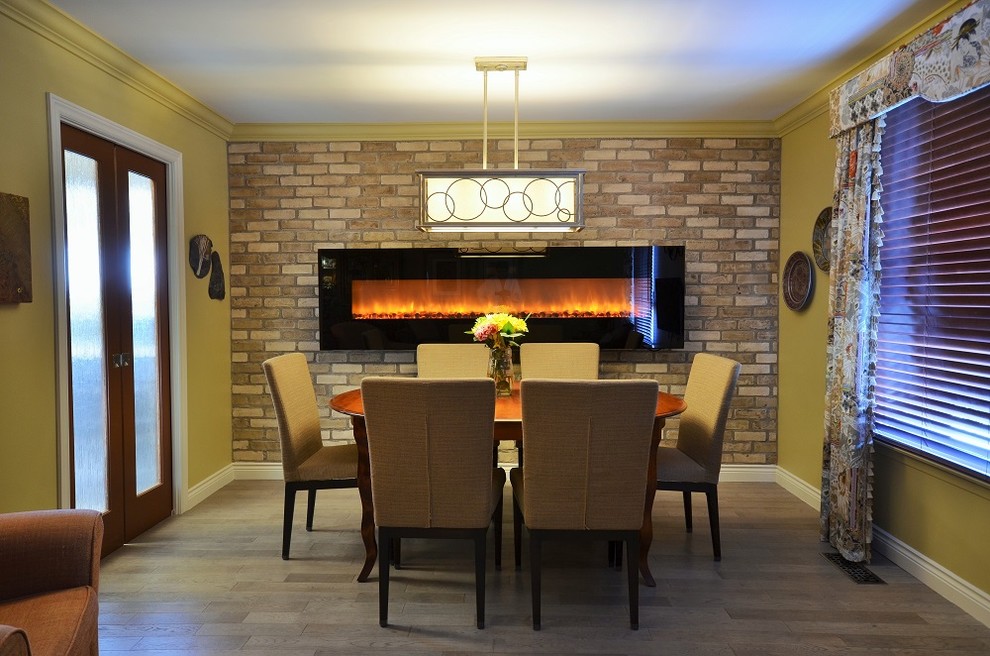 This is an example of a mid-sized eclectic separate dining room in Toronto with yellow walls, light hardwood floors, a ribbon fireplace and a brick fireplace surround.