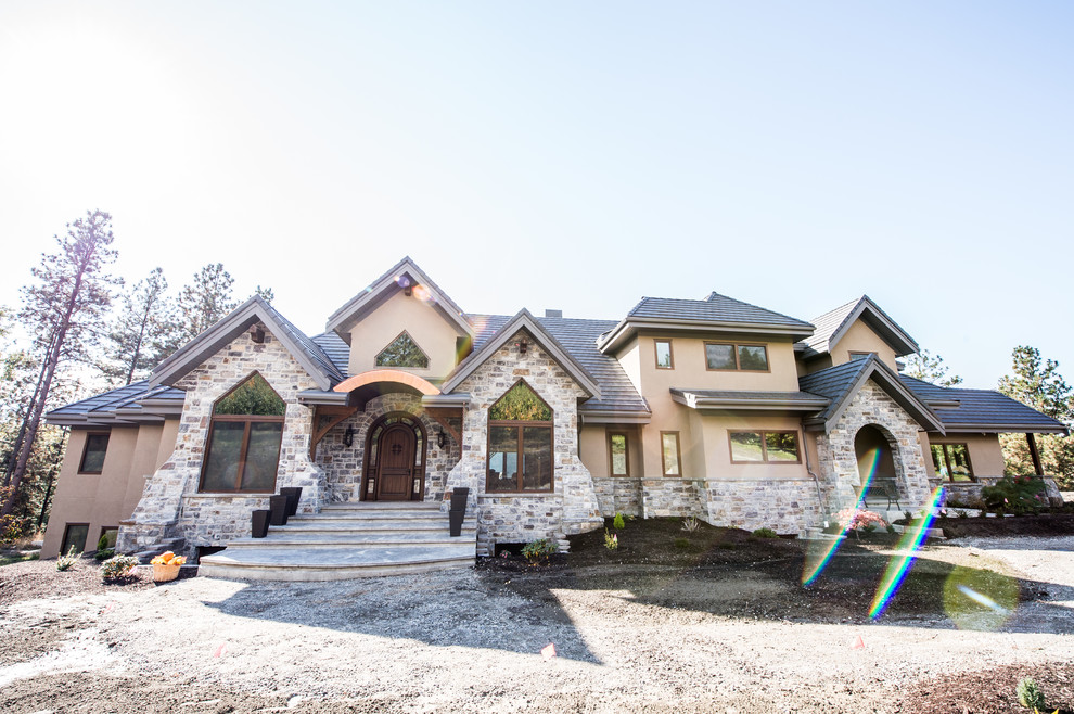 This is an example of a large country two-storey house exterior in Vancouver with stone veneer.