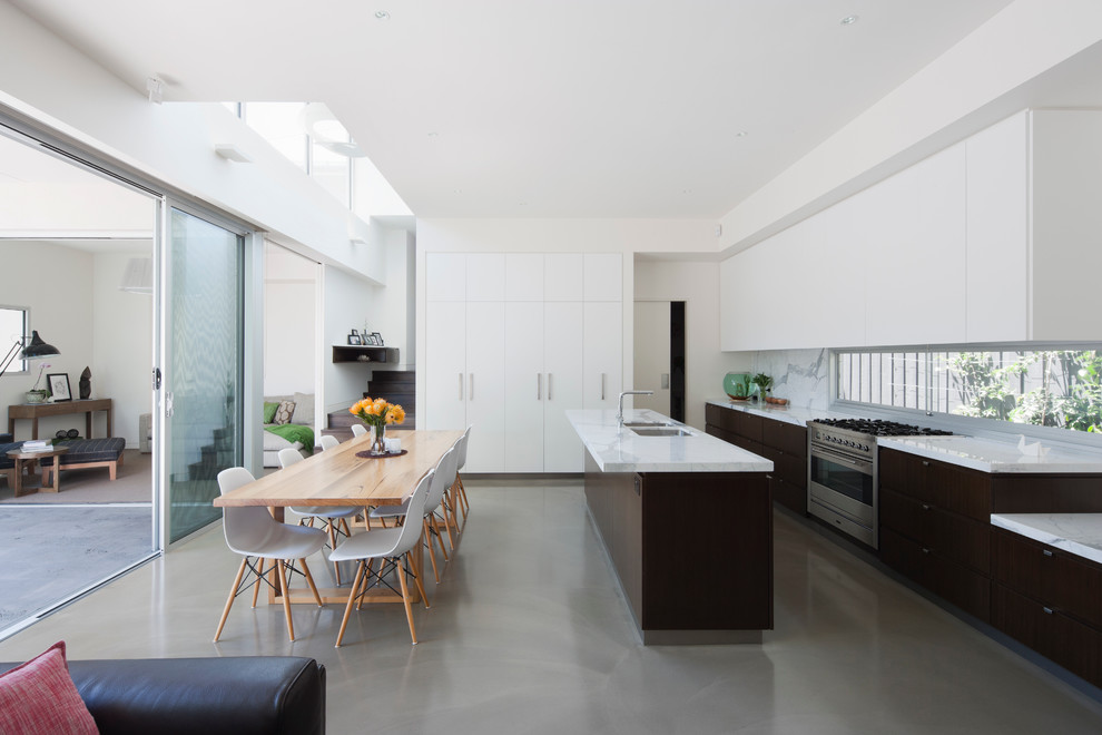 This is an example of a modern galley eat-in kitchen in Melbourne with an undermount sink, marble benchtops, stainless steel appliances, concrete floors and with island.