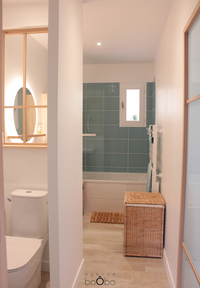 Photo of a small scandinavian master bathroom in Bordeaux with a one-piece toilet, white walls, ceramic floors, beige floor, blue tile, flat-panel cabinets, light wood cabinets, an alcove tub, porcelain tile, a console sink, solid surface benchtops, an open shower, white benchtops, an enclosed toilet, a single vanity and a freestanding vanity.