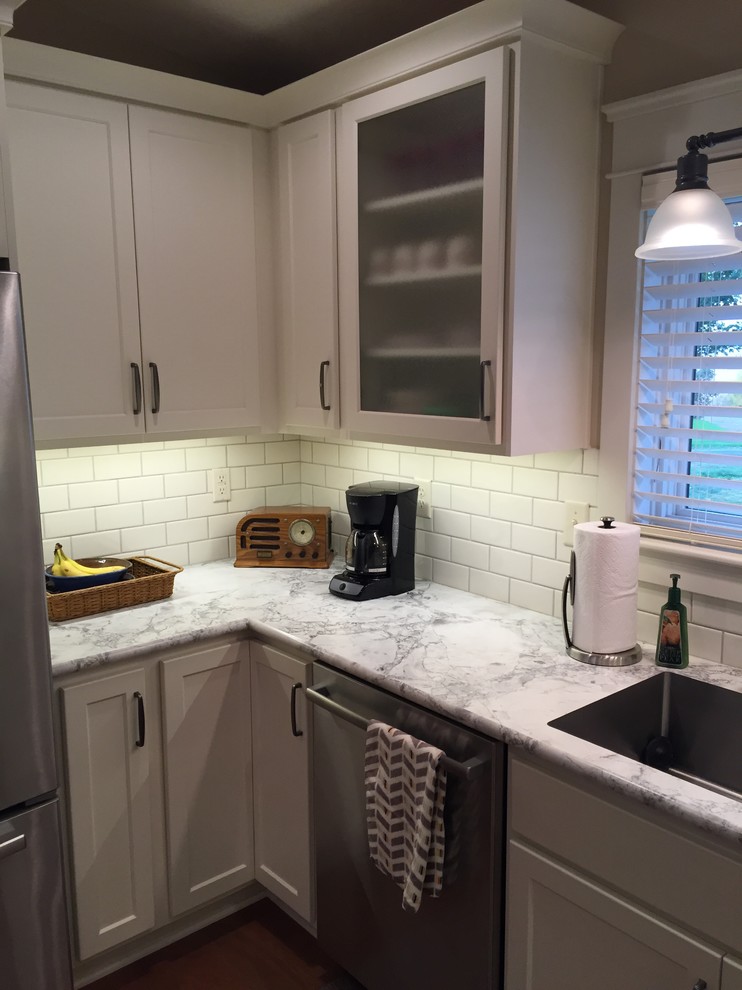 Example of a mid-sized transitional u-shaped medium tone wood floor eat-in kitchen design with an integrated sink, shaker cabinets, white cabinets, laminate countertops, white backsplash, subway tile backsplash, stainless steel appliances and a peninsula