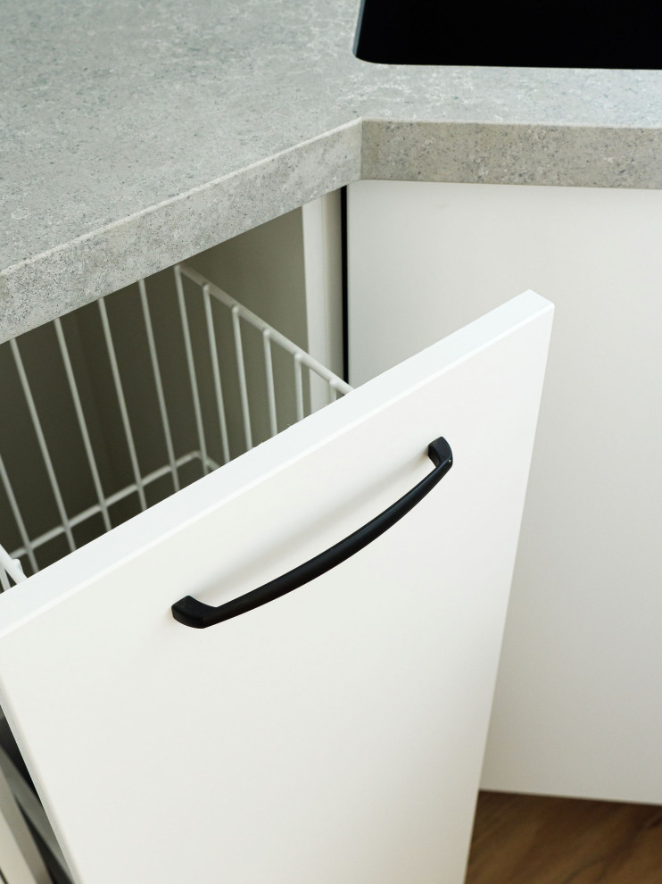 Photo of a small transitional l-shaped laundry room in Melbourne with an undermount sink, white cabinets, blue splashback, subway tile splashback, white walls, vinyl floors, brown floor and grey benchtop.