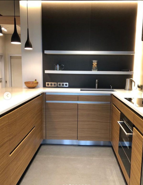 Inspiration for a mid-sized contemporary u-shaped eat-in kitchen in Saint Petersburg with flat-panel cabinets, light wood cabinets, quartz benchtops, black splashback, a peninsula and white benchtop.