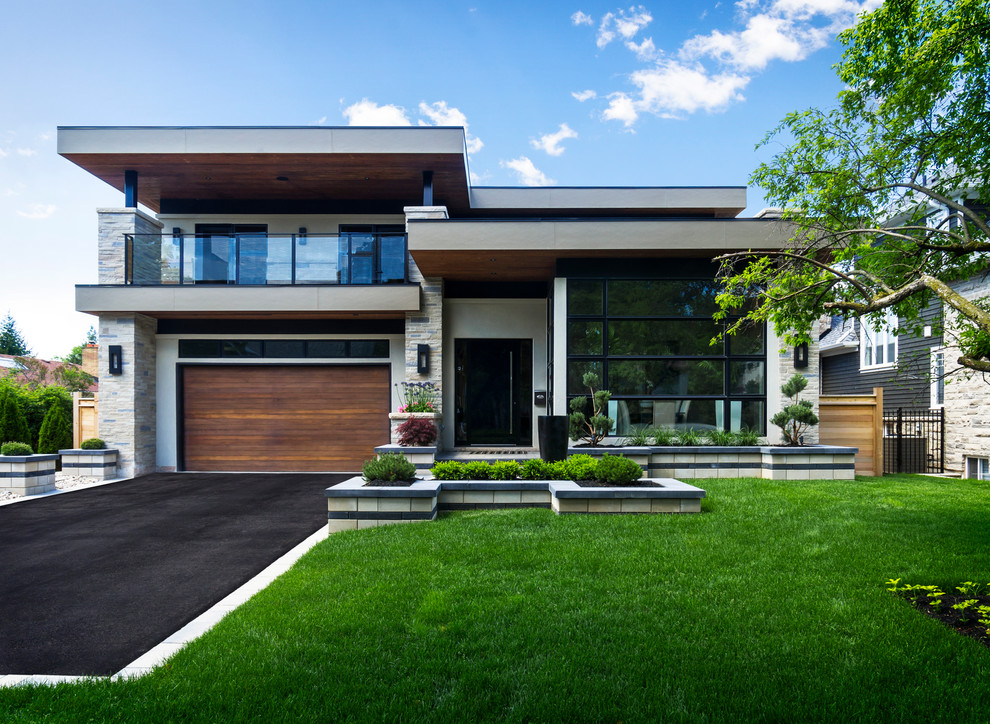 Photo of a large contemporary two-storey stucco white house exterior in Toronto with a flat roof.