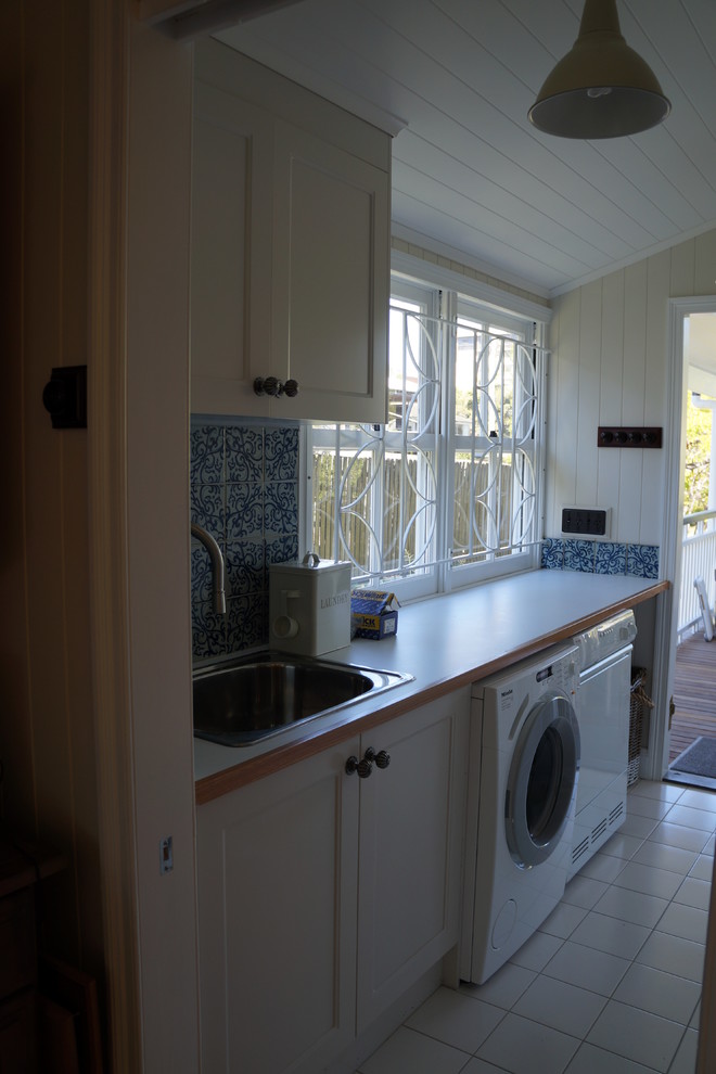 Design ideas for a mid-sized traditional galley dedicated laundry room in Brisbane with a drop-in sink, shaker cabinets, white cabinets, laminate benchtops, ceramic floors and a side-by-side washer and dryer.