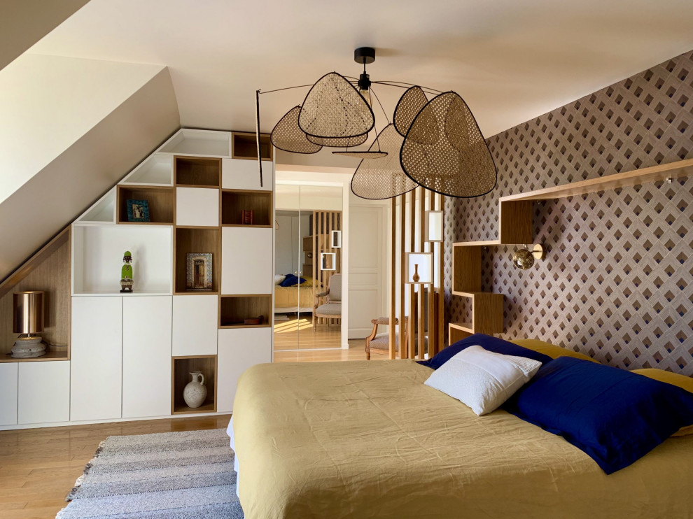 Modelo de dormitorio principal contemporáneo grande sin chimenea con paredes azules, suelo de madera clara, suelo beige y papel pintado