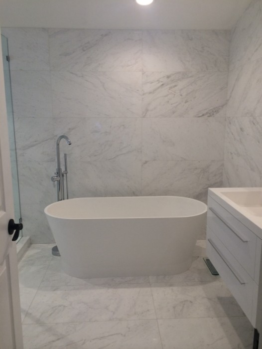 Large contemporary master bathroom in Miami with flat-panel cabinets, white cabinets, a freestanding tub, a corner shower, yellow tile, marble, white walls, marble floors, an integrated sink, marble benchtops, white floor and a hinged shower door.