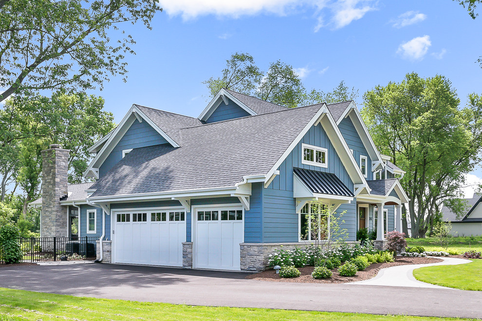 This is an example of a large arts and crafts two-storey blue house exterior in Chicago with a gable roof, a shingle roof and wood siding.