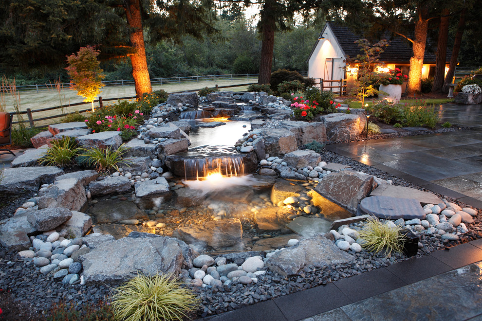 Photo of a large contemporary backyard partial sun xeriscape for summer in Seattle with with waterfall and natural stone pavers.