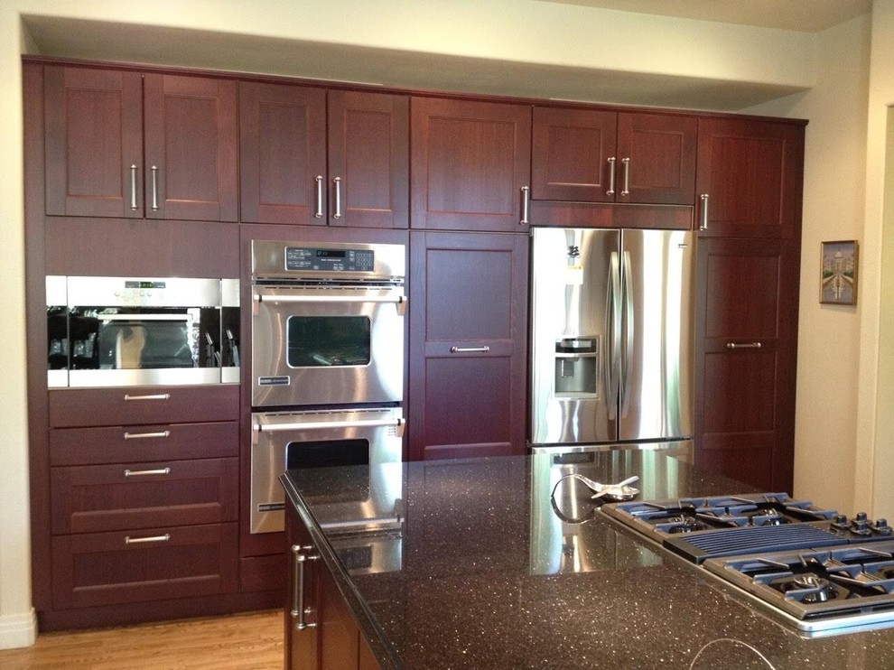 This is an example of a mid-sized transitional single-wall separate kitchen in Denver with a double-bowl sink, terrazzo benchtops, beige splashback, subway tile splashback, stainless steel appliances, medium hardwood floors, with island, beige floor, recessed-panel cabinets and dark wood cabinets.
