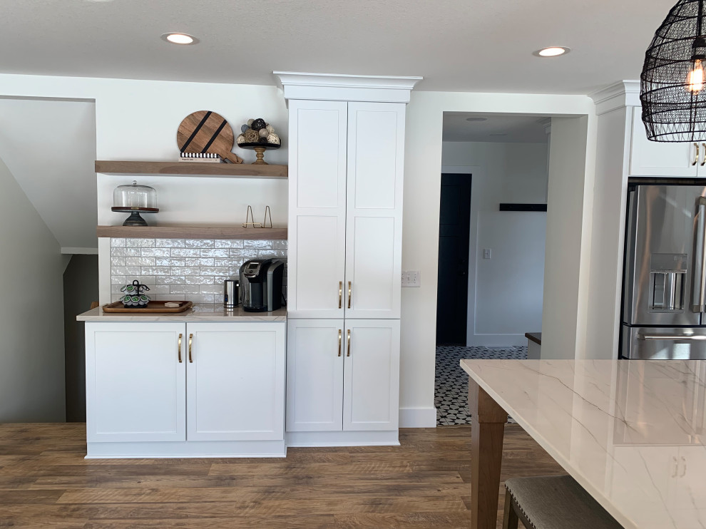 Inspiration for a transitional l-shaped vinyl floor and brown floor eat-in kitchen remodel with an undermount sink, shaker cabinets, white cabinets, quartz countertops, stainless steel appliances, an island and gray countertops