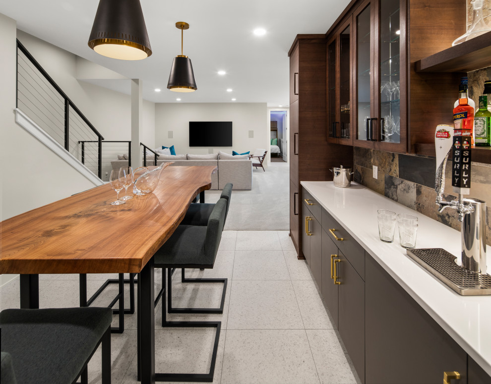 Photo of a mid-sized modern galley seated home bar in Minneapolis with flat-panel cabinets, dark wood cabinets, wood benchtops, multi-coloured splashback, cement tile splashback, ceramic floors, white floor and white benchtop.