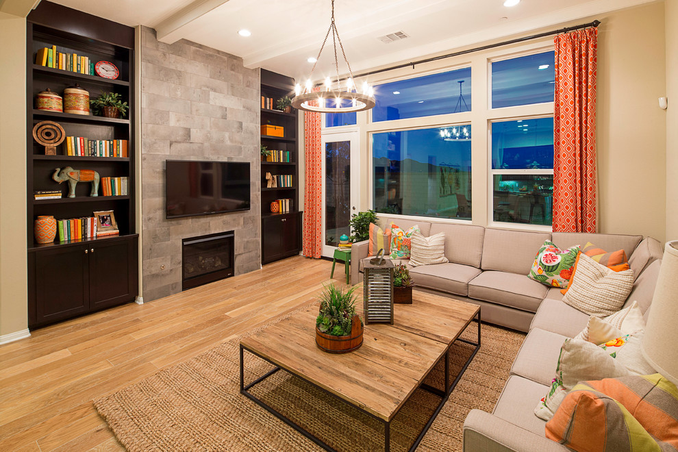 Mid-sized contemporary enclosed living room in Los Angeles with beige walls, light hardwood floors, a standard fireplace, a wall-mounted tv, a library, a tile fireplace surround and beige floor.