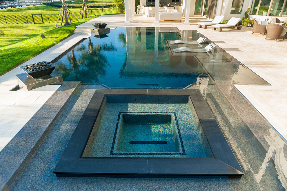 Inspiration for a large contemporary backyard custom-shaped infinity pool in Miami with a hot tub and tile.