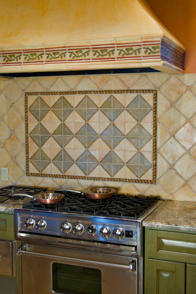 This is an example of a mid-sized mediterranean u-shaped eat-in kitchen in Albuquerque with raised-panel cabinets, green cabinets, granite benchtops, multi-coloured splashback, terra-cotta splashback and stainless steel appliances.