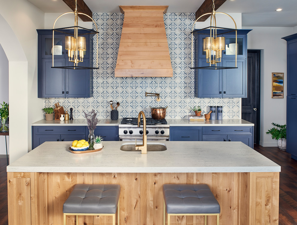 Inspiration for a large mediterranean l-shaped eat-in kitchen in San Diego with an undermount sink, shaker cabinets, blue cabinets, solid surface benchtops, blue splashback, porcelain splashback, stainless steel appliances, with island, brown floor and grey benchtop.