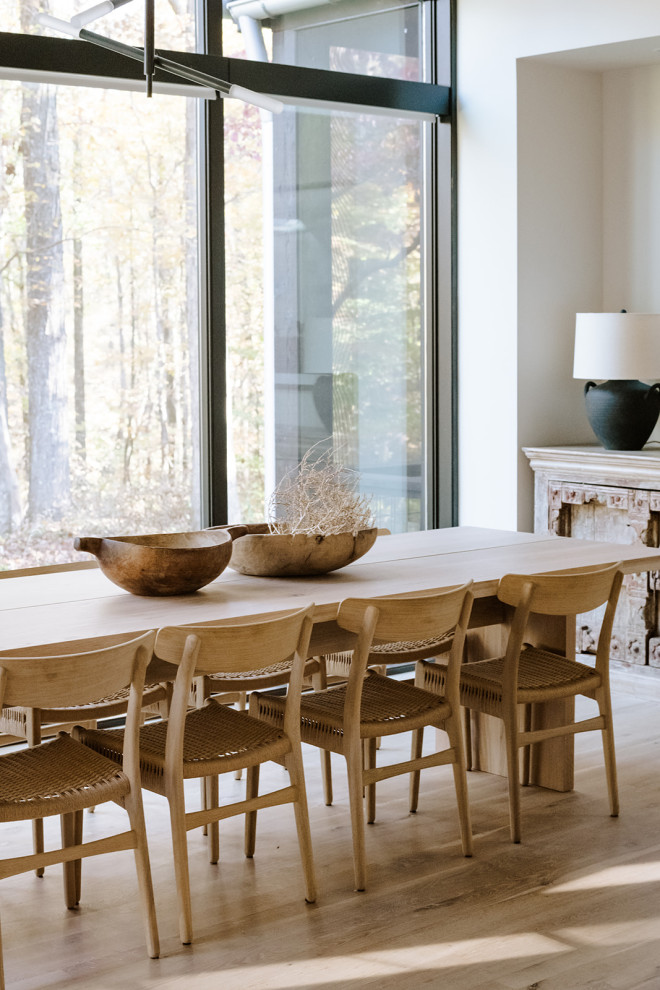 Immagine di una grande sala da pranzo aperta verso il soggiorno minimalista con pareti bianche e parquet chiaro