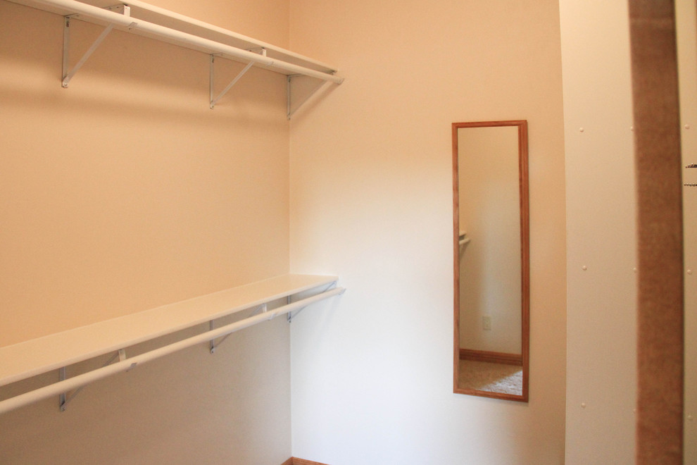 Photo of a small traditional gender-neutral walk-in wardrobe in Other with open cabinets, white cabinets and carpet.