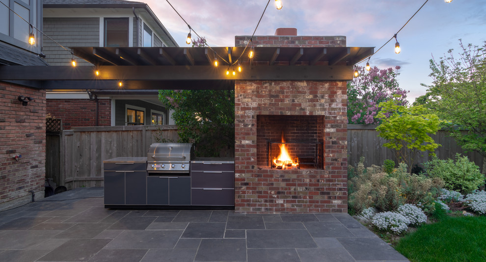 Mid-sized contemporary backyard patio in Seattle with with fireplace, natural stone pavers and an awning.