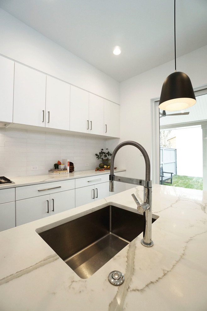 Photo of a small modern l-shaped separate kitchen in Richmond with an undermount sink, flat-panel cabinets, white cabinets, quartz benchtops, white splashback, ceramic splashback, stainless steel appliances, ceramic floors, with island, black floor and white benchtop.