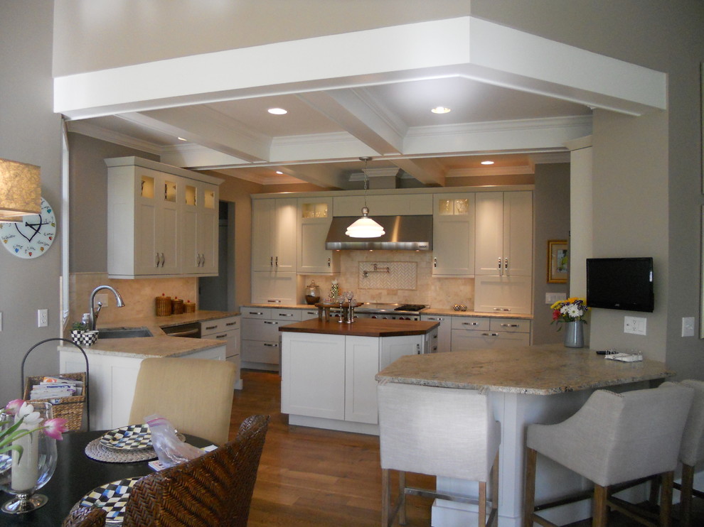 Inspiration for a large transitional u-shaped medium tone wood floor eat-in kitchen remodel in New York with an undermount sink, recessed-panel cabinets, white cabinets, granite countertops, multicolored backsplash, porcelain backsplash, stainless steel appliances, gray walls and an island