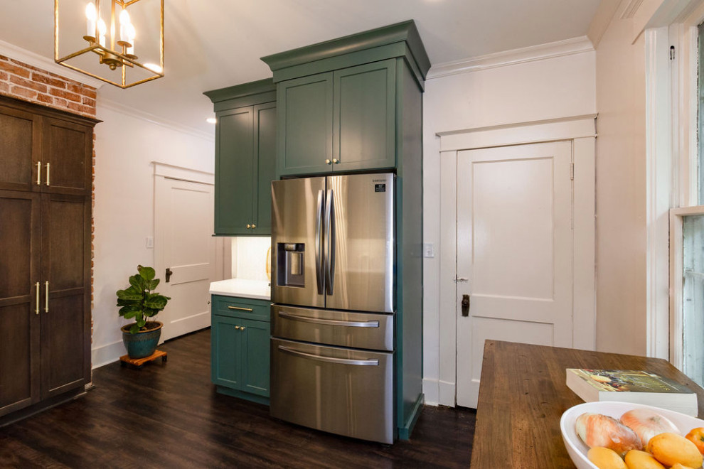 Example of a small l-shaped vinyl floor and brown floor enclosed kitchen design with a farmhouse sink, shaker cabinets, green cabinets, quartz countertops, white backsplash, marble backsplash, stainless steel appliances, no island and white countertops