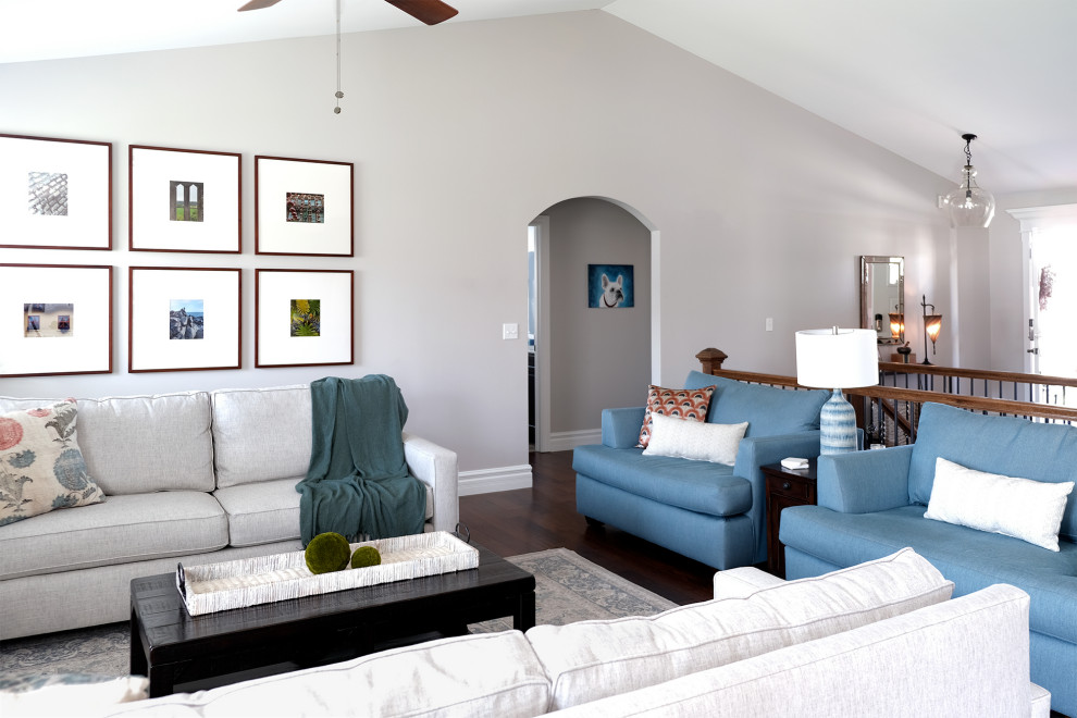 На фото: большая открытая гостиная комната в стиле неоклассика (современная классика) с серыми стенами, темным паркетным полом, стандартным камином, фасадом камина из дерева и сводчатым потолком с