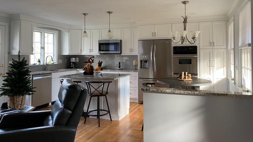 Mid-sized transitional l-shaped light wood floor and beige floor open concept kitchen photo in Bridgeport with an undermount sink, shaker cabinets, white cabinets, granite countertops, gray backsplash, subway tile backsplash, stainless steel appliances, an island and gray countertops